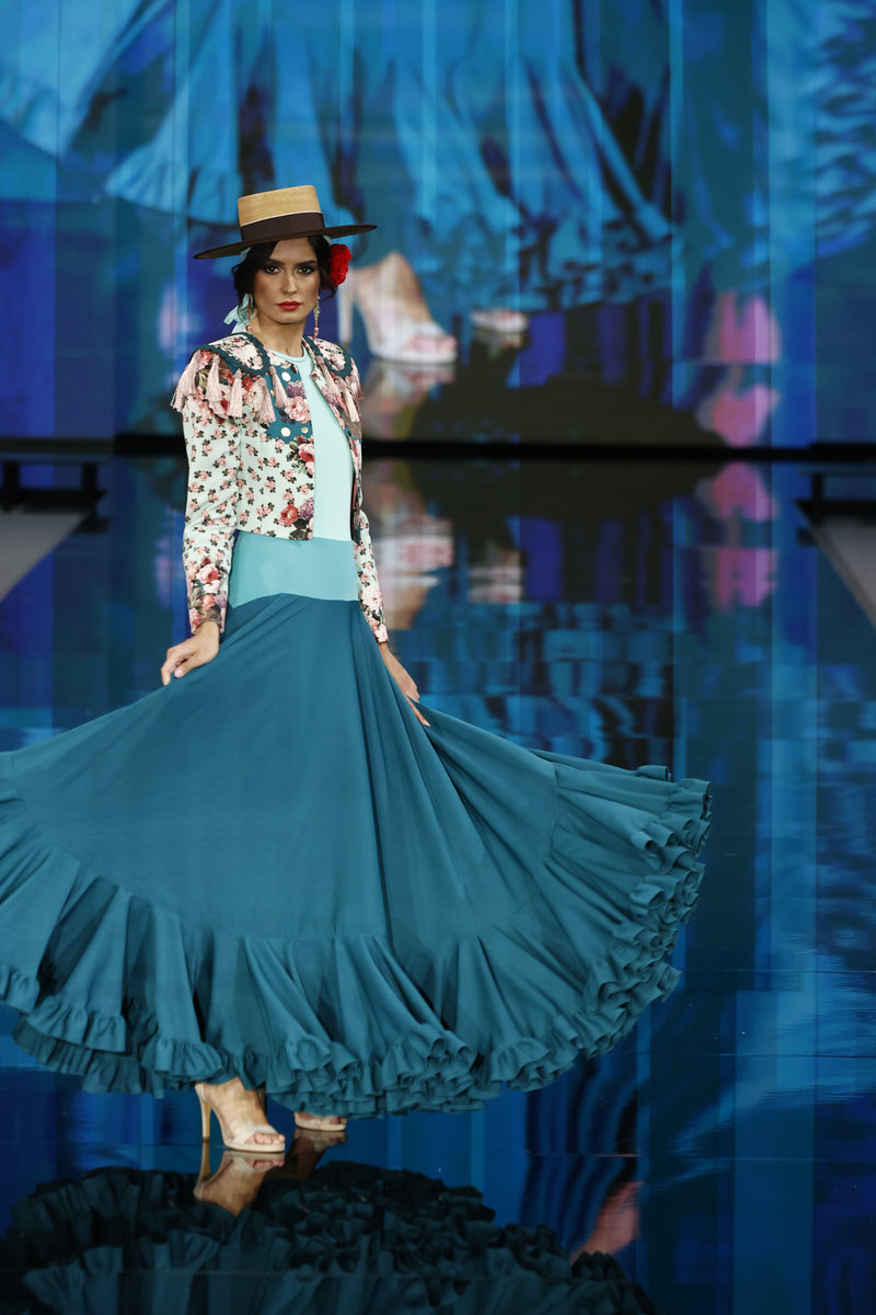 Vestido con cuello a la caja, gran vuelo y un degradado de tonos verdes agua. Adornado con una torera de estampado floral.