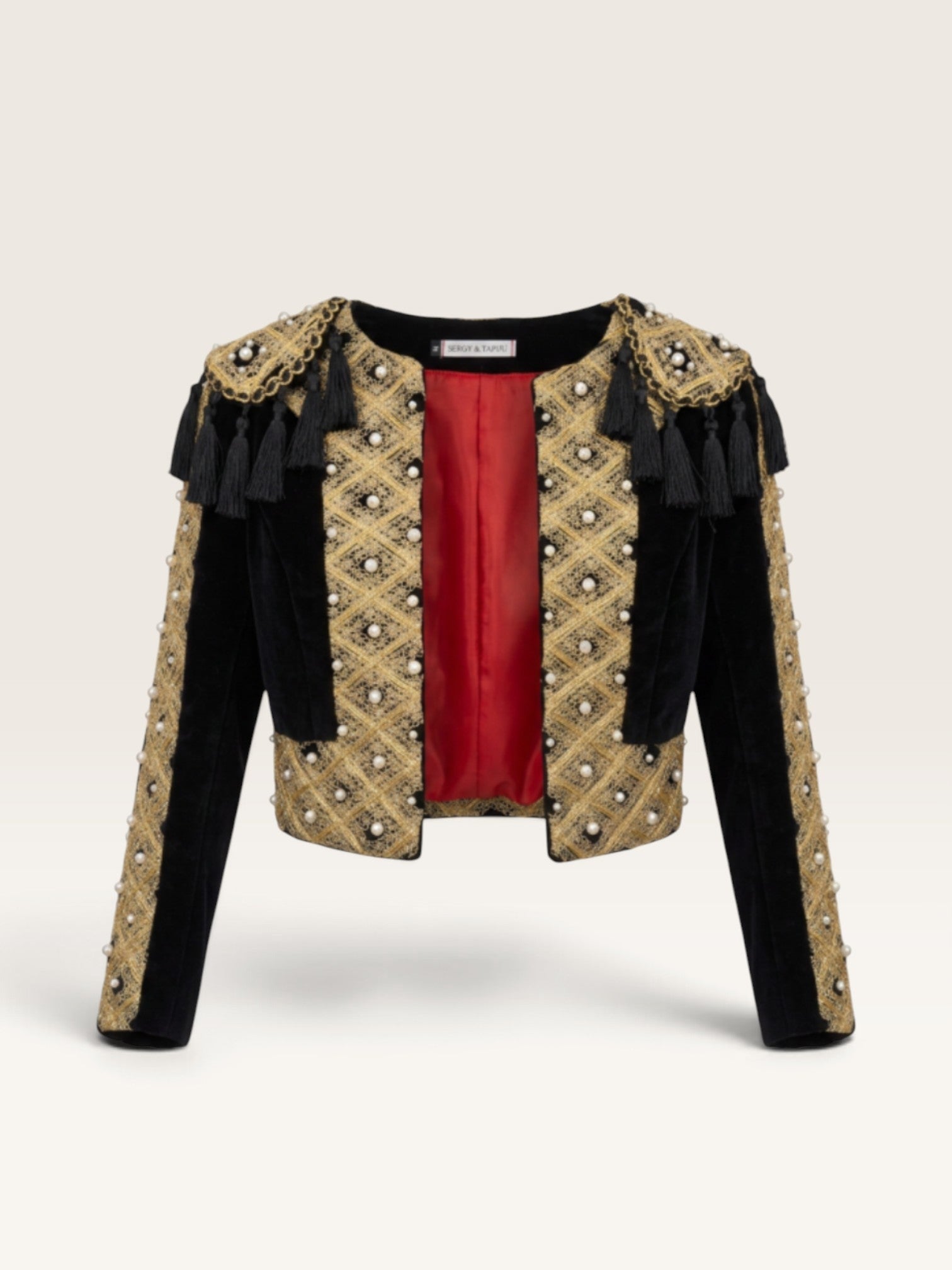 Torera negra de terciopelo Sergy & Tapiju con bordados dorados, perlas y forro rojo, estilo torero artesanal.