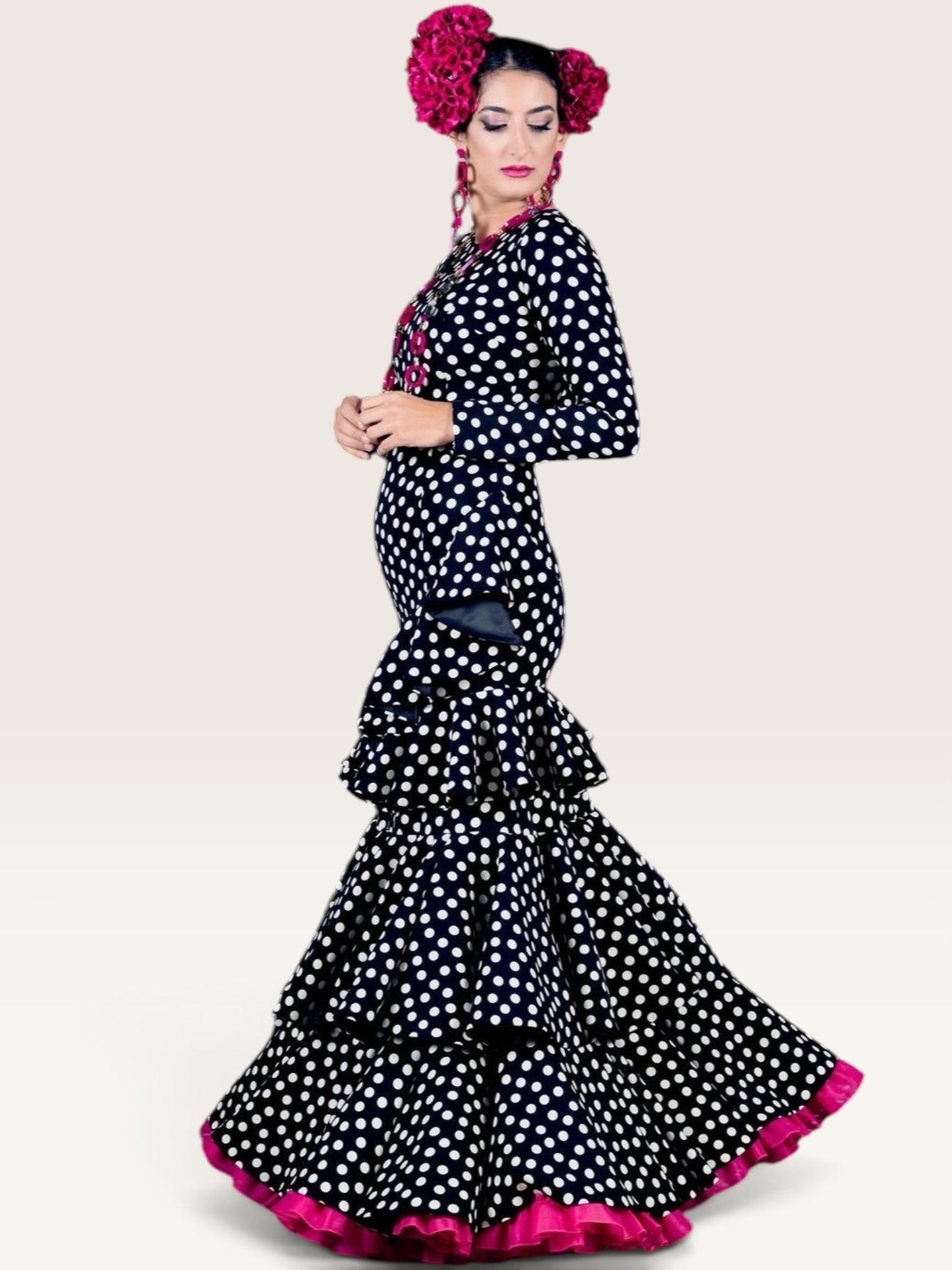 Modelo con traje de flamenca Sergy & Tapiju negro de lunares blancos, manga ajustada y tres volantes estructurados.