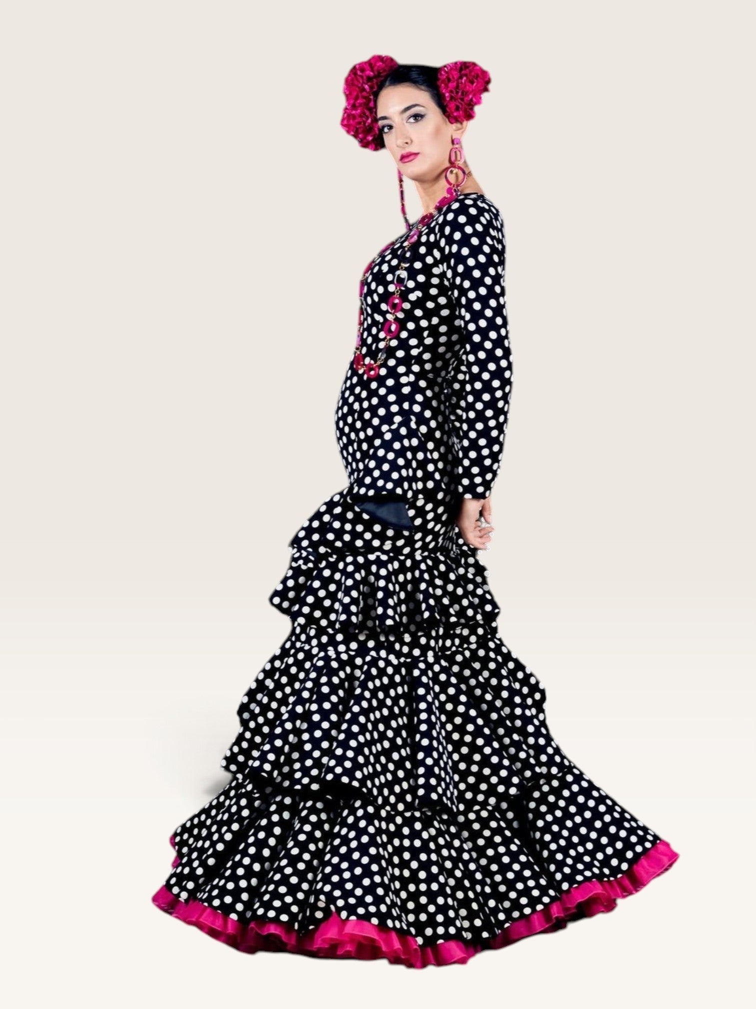 Modelo con traje de flamenca Sergy & Tapiju negro de lunares blancos, manga ajustada, tres volantes y detalles fucsia